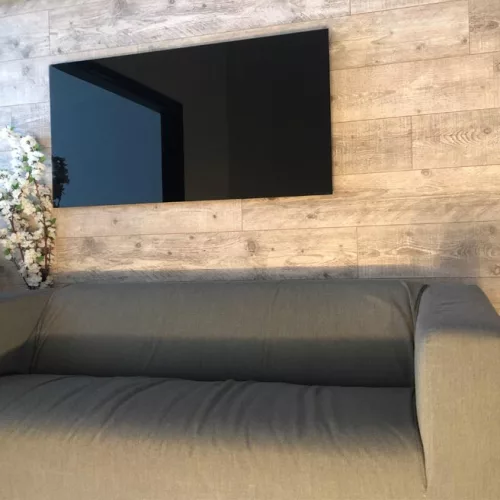 Prémium, fehér üveg infrapanel egy modern, minimalista nappali falán, egy elegáns kanapé fölött 600W