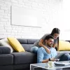 Prémium, fehér üveg infrapanel egy modern, minimalista nappali falán, egy elegáns kanapé fölött 800W